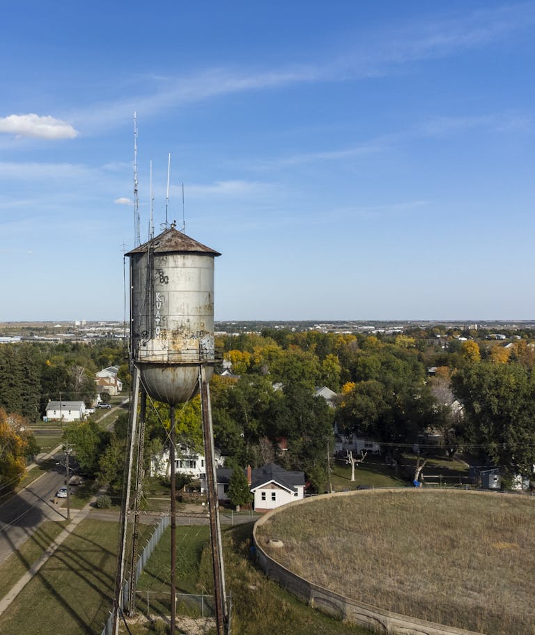 Aerial view of a historic water tower in Minot, ND under a clear blue sky. Minot, ND is one of the communities with Amtrak in North Dakota.
