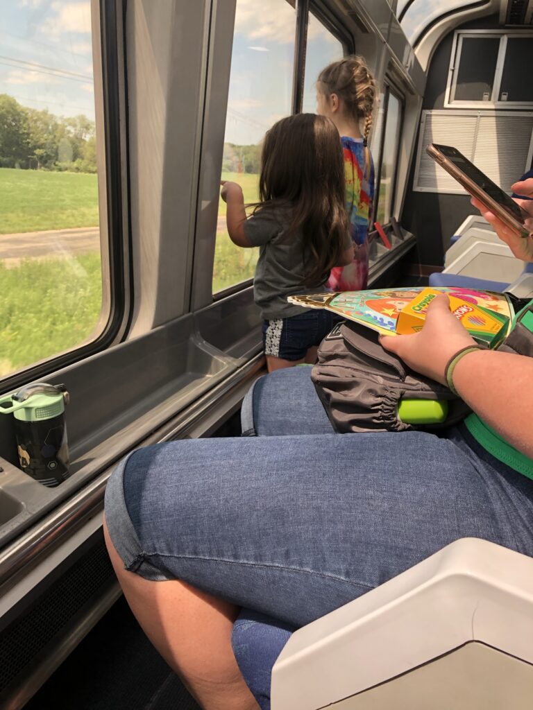 Kids in a Sightseer lounge playing and looking out the window  great entertainment on Amtrak. 