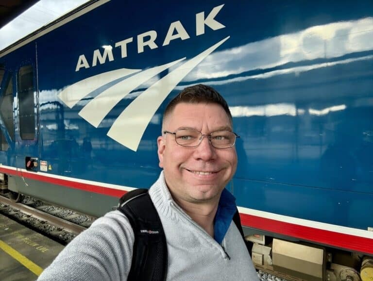 Kev infront of an Amtrak locomtive with the logo in the background,